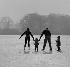 an adult and two children are walking in the snow with their arms around each other