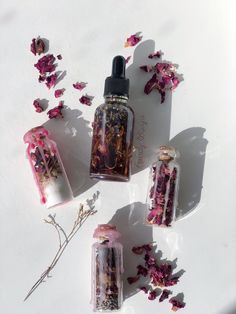 three bottles filled with different types of flowers on top of a white surface next to each other