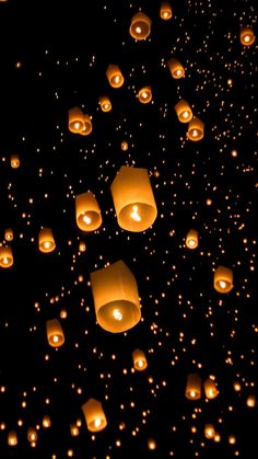 many lit up lanterns floating in the air