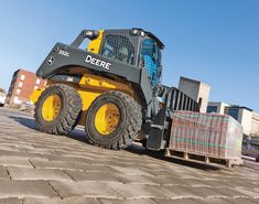 a yellow and black skid steer sitting on top of a brick road