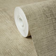 a roll of beige fabric on top of a white table cloth with an adhesive tape