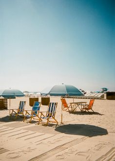 beach chairs and umbrellas on the sand near the ocean