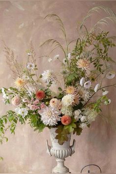 a vase filled with lots of flowers sitting on top of a table next to a wall