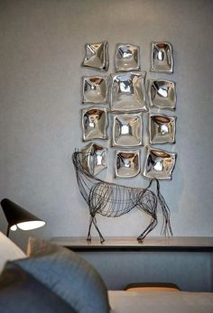 a metal horse sculpture sitting on top of a table next to a wall mounted mirror