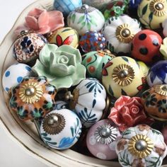 a bowl filled with lots of different colored knobs on top of a white table