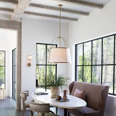 a dining room table with two chairs and a lamp hanging from the ceiling over it