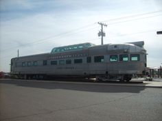 a silver train car sitting on the side of a road