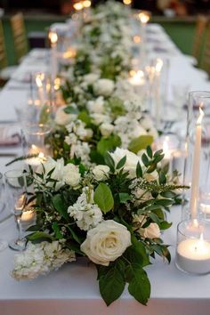 a long table with white flowers and candles