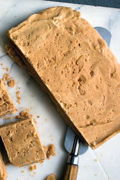 peanut butter fudge cake sitting on top of a cutting board next to a knife