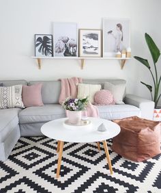 a living room filled with furniture and pictures hanging on the wall above a white coffee table