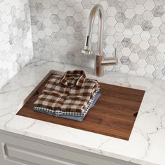 a wooden cutting board sitting on top of a counter next to a faucet