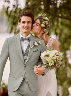 a man in a suit and tie is kissing a woman's face with flowers on her head