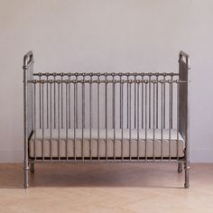 a metal crib sitting on top of a hard wood floor next to a wall