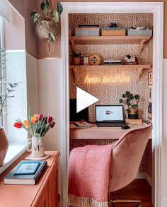 a desk with a laptop on top of it next to a shelf filled with flowers