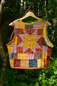 a quilted vest hanging from a tree in the woods