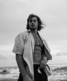 a man with long hair standing on the beach