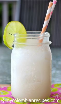 a mason jar filled with white liquid and a lime slice next to it on a table