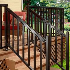 a wooden deck with black railing and handrails next to a red chair on the grass