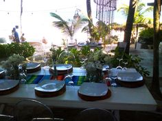 the table is set with plates and flowers in vases on it, along with other place settings