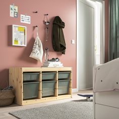 a bedroom with pink walls, white furniture and storage bins on the sideboard