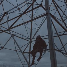 a man climbing up the side of a tall metal structure on a cloudy day in winter