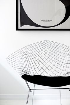 a black and white chair sitting in front of a framed art print on the wall