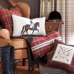 pillows and boots are sitting on the floor in front of a chair with a plaid pillow