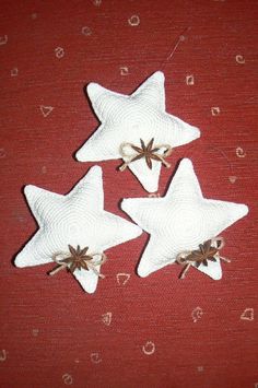 three white star shaped ornaments on a red surface