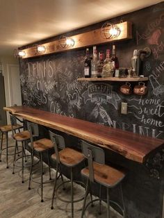 a bar with several stools in front of it and chalk writing on the wall