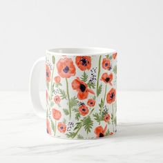 an orange and green floral pattern on a white coffee mug sitting on a marble surface