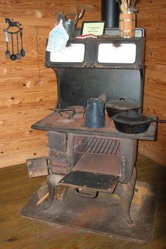 an old fashioned wood stove with pots and pans on it's burners