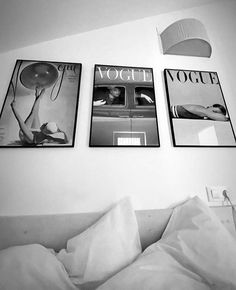 three black and white photographs hang on the wall above a bed with pillows, sheets, and lamps