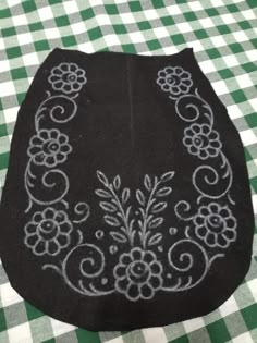 a black bag with white flowers on it sitting on a checkered tablecloth covered table