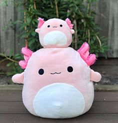 a pink stuffed animal sitting on top of a wooden floor next to a tree and fence