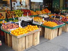 several wooden boxes filled with oranges and other fruit on display in front of a store