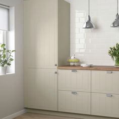 a kitchen with white cabinets and green plants