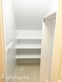 an empty walk in closet with white walls and shelving unit on the bottom floor