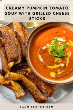 a bowl of creamy pumpkin tomato soup with grilled cheese sticks on a white plate