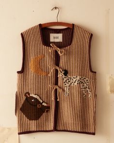 a sweater vest with animals on it hanging from a hook in a wall next to a door