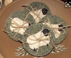 three sheep coasters on top of a plate with twine and twine around them