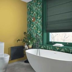 a bathroom with green and yellow wallpaper next to a white bathtub in front of a window