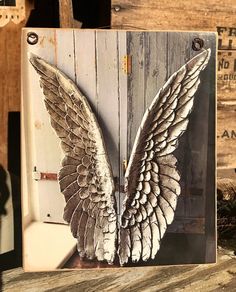 an image of two white wings on a wooden paneled wall in a frame with the door open