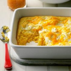 a casserole dish with cheese on top and a spoon next to the casserole