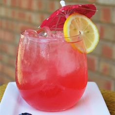 a red drink sitting on top of a white plate next to a blueberry slice