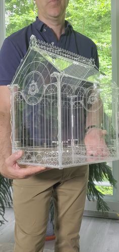 a man is holding a bird cage in his hands