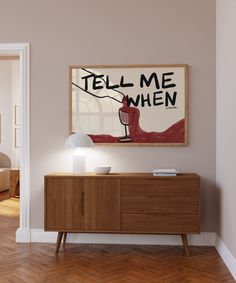 a painting hanging on the wall above a wooden cabinet in a room with hardwood floors