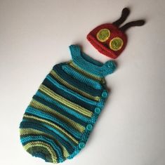 a crocheted baby's sleeping bag with a knitted caterpillar on top