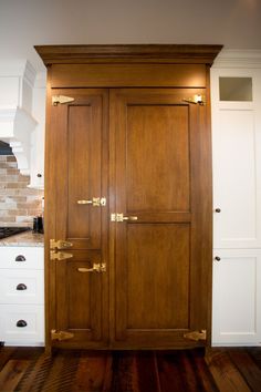 an open wooden cabinet in the middle of a kitchen