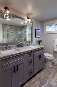 a bathroom with two sinks and a large mirror above the sink, along with a toilet