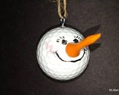 a golf ball ornament with a snowman face on it's side